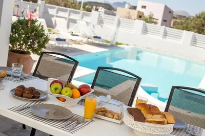 a table with a breakfast of fruit and bread next to a pool at La Casa Del Amor in Kalithies