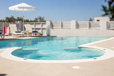 a pool with blue water and chairs and an umbrella at La Casa Del Amor in Kalithies