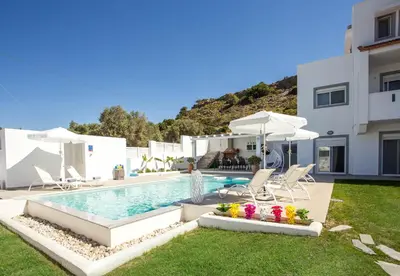 a swimming pool with chairs and umbrellas next to a building at La Casa Del Amor in Kalithies