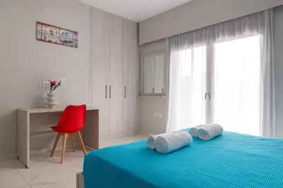 a bedroom with a blue bed and a red chair at Villa Divina in Kremasti