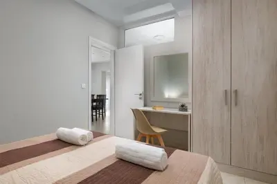 a bedroom with two beds and a desk with a chair at Villa Divina in Kremasti