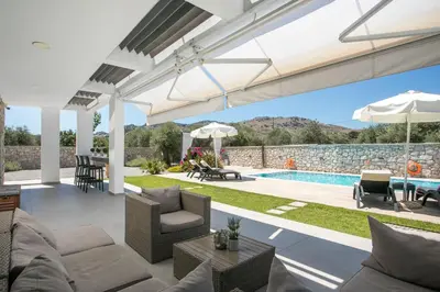 a living room with a patio and a swimming pool at Modern Villa with Pool & Garden Kastalys, Rhodes in Kalithies