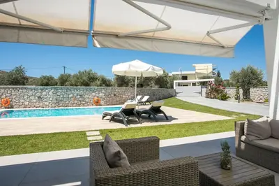 a patio with chairs and an umbrella and a pool at Modern Villa with Pool & Garden Kastalys, Rhodes in Kalithies