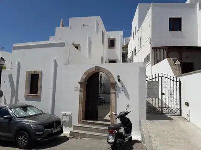 a motorcycle parked in front of a white building at PHILIPPOS STUDIOS & APT in Líndos