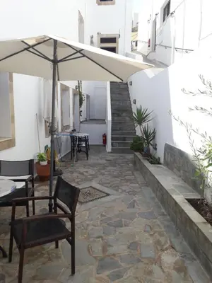 a patio with an umbrella and a table and chairs at PHILIPPOS STUDIOS & APT in Líndos
