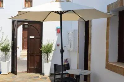 a table with an umbrella in front of a building at PHILIPPOS STUDIOS & APT in Líndos