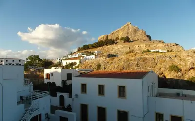 a group of white buildings and a mountain at PHILIPPOS STUDIOS & APT in Líndos