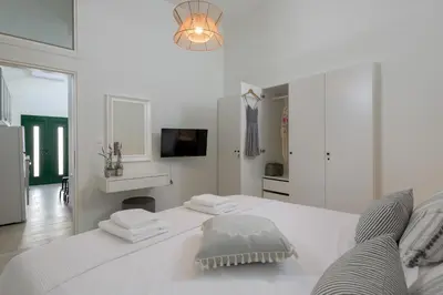 a white bedroom with a white bed and a tv at Kite Blue Villas in Kattavía