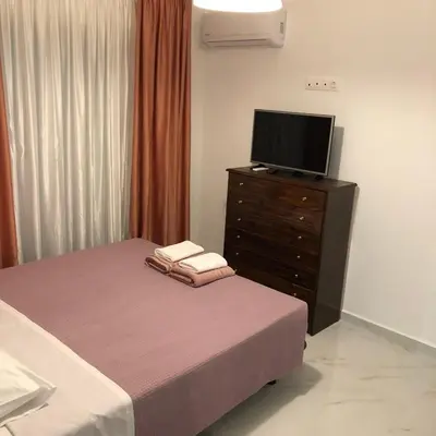 a bedroom with a bed and a dresser with a television at Chrysanthi’s in Faliraki