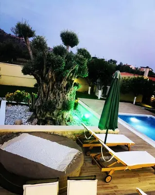 a pool with a green umbrella and chairs next to a pool at Villa MATA - 600m² with Private Pool and Jacuzzi in Kalithies