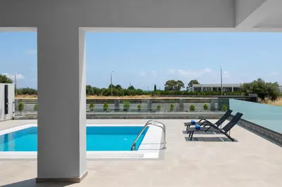 a swimming pool with two chairs next to a building at Armonia Suites in Gennadi