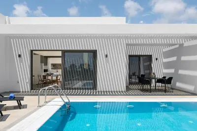 a villa with a swimming pool next to a house at Armonia Suites in Gennadi