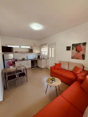 a living room with a red couch and a table at Archangelos Garden House in Archangelos