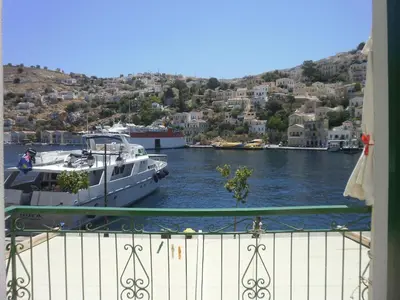 a boat is docked in a river with houses at Harbour View Apartment in Symi