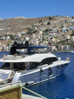a white boat docked at a dock in the water at Harbour View Apartment in Symi