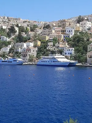 two boats in the water in front of a city at Harbour View Apartment in Symi