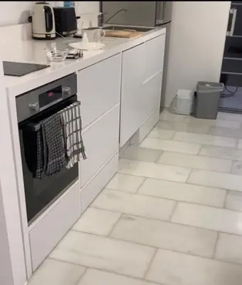 a kitchen with white cabinets and a tile floor at Panoramic view - Penthouse in Rhodes Town