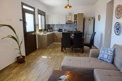 a living room with a couch and a table and a kitchen at Blue Bay Villas , Ground Floor in Archangelos
