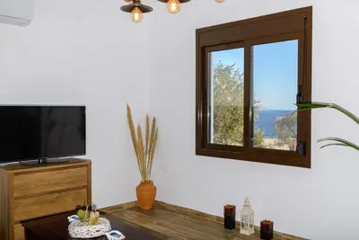 a living room with a tv and a window at Blue Bay Villas , Ground Floor in Archangelos