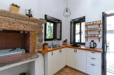 a kitchen with white cabinets and a brick fireplace at Letty's House - Old Town Luxury Mansion in Rhodes Town