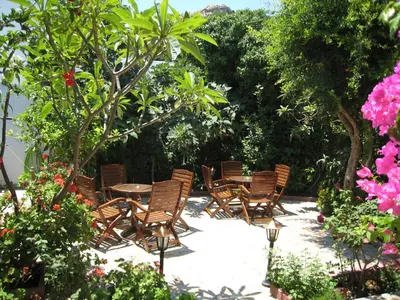 a group of chairs and tables in a garden at Eleftheria Lindian Studios II in Líndos