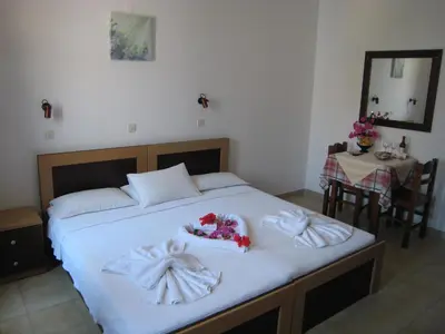 a bedroom with a bed with white sheets and flowers on it at Eleftheria Lindian Studios II in Líndos