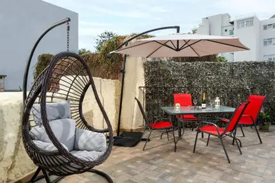 a patio with a table and chairs and an umbrella at Niochori apartments 2 in Rhodes Town