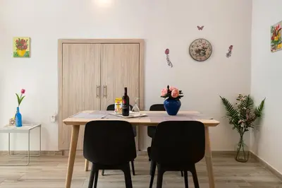 a dining room table with two chairs and a bottle of wine at Niochori apartments 2 in Rhodes Town