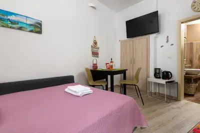 a bedroom with a pink bed and a table at Niochori apartments 3 in Rhodes Town