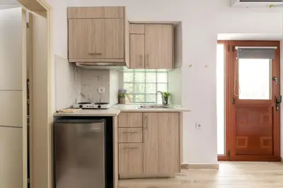 a kitchen with wooden cabinets and a stainless steel refrigerator at Niochori apartments 3 in Rhodes Town