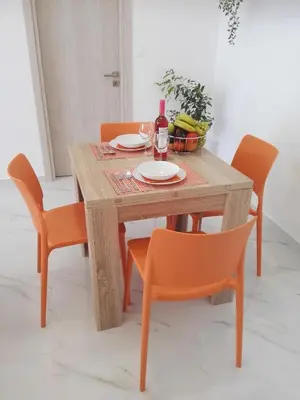 a wooden table with orange chairs and a bottle of wine at Bouganville apartment Stegna in Archangelos