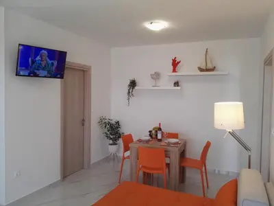 a living room with a table and chairs and a tv at Bouganville apartment Stegna in Archangelos