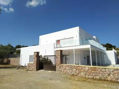 a white house with a stone wall at Bouganville apartment Stegna in Archangelos