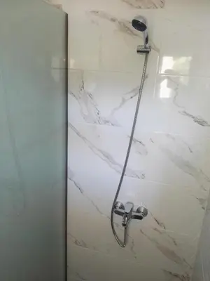 a shower in a bathroom with white marble at Bouganville apartment Stegna in Archangelos