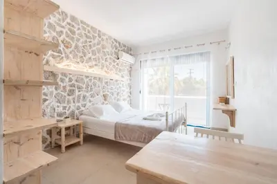 a bedroom with a bed and a stone wall at Studios Maria Christina in Faliraki
