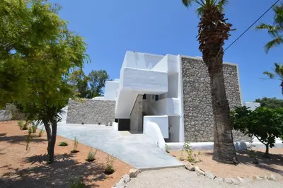 a white house with a palm tree in front of it at Studios Maria Christina in Faliraki