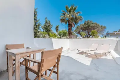 a patio with a table and chairs and a palm tree at Studios Maria Christina in Faliraki