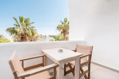 a table and chairs on a balcony with palm trees at Studios Maria Christina in Faliraki