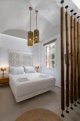a white bedroom with a white bed and two lights at Legato House in Rhodes Town