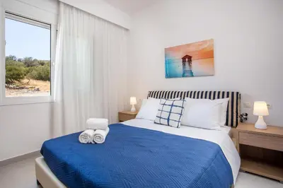 a bedroom with a blue and white bed and a window at Kalathos Sea View House in Kalathos