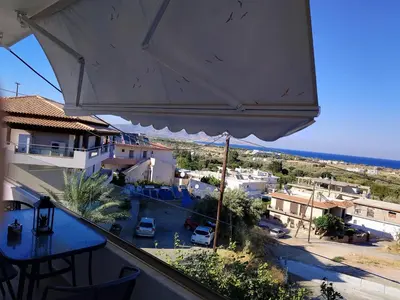 a balcony with a table and an umbrella at Kalathos Sea View House in Kalathos