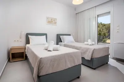 two beds in a room with a window at Kalathos Sea View House in Kalathos
