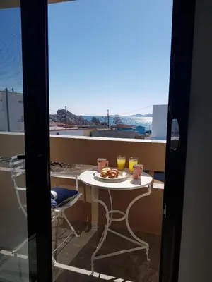 a table with a plate of food and drinks on a balcony at Sea Breeze 2 in Haraki