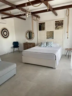 a bedroom with a large bed and a blue chair at Oliva in Faliraki