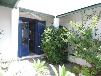 a blue door on a white house with bushes at Exclusive apartment in Ecovilla on the beach in Apolakkiá