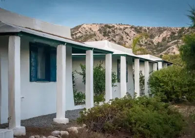 a row of white houses with mountains in the background at Exclusive apartment in Ecovilla on the beach in Apolakkiá