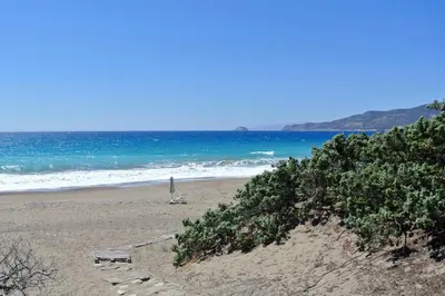 a person standing on a beach with the ocean at Exclusive apartment in Ecovilla on the beach in Apolakkiá