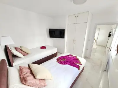 a white room with two beds and a tv at Monte Smith City Home in Rhodes Town