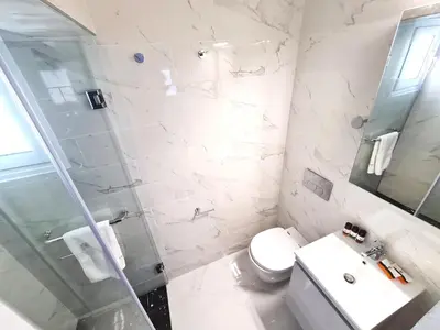 a white bathroom with a toilet and a sink at Monte Smith City Home in Rhodes Town