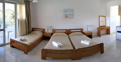 a room with two beds in a room with a window at Artemis Studios - Pool and garden in Koskinou